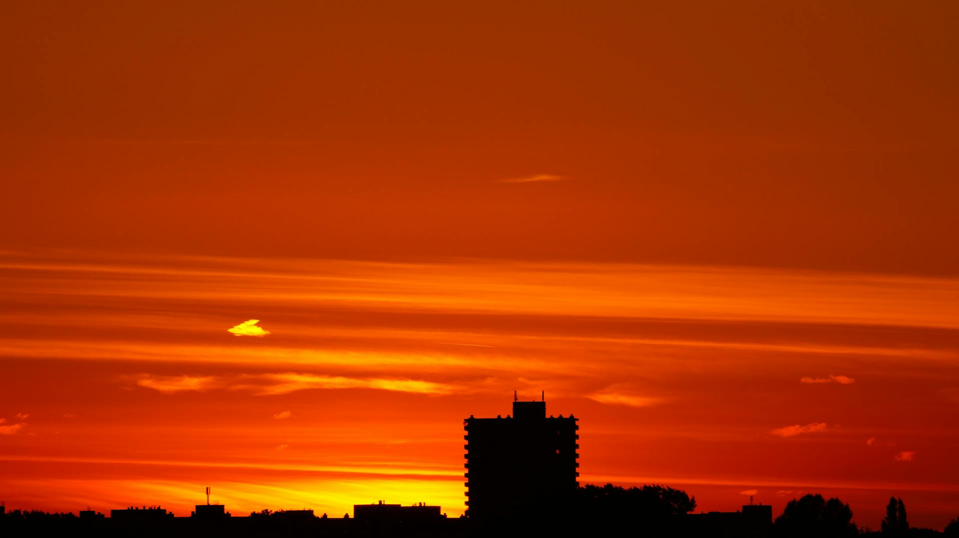 Capture of a city skyline silhouette against a vivid orange sunset sky.