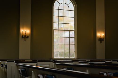 Free Spacious church interior with stained glass window and traditional pews, invoking serenity. Stock Photo