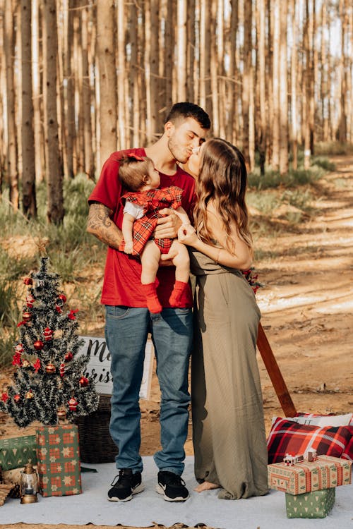 A Family Standing on a Blanket with Christmas Decorations in a Park and Smiling 