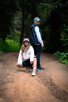 A couple posing stylishly on a forest trail, exhibiting a sense of adventure and casual fashion.
