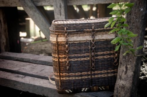 Free A detailed view of a handmade wicker basket set on a rustic wooden bench outdoors. Stock Photo