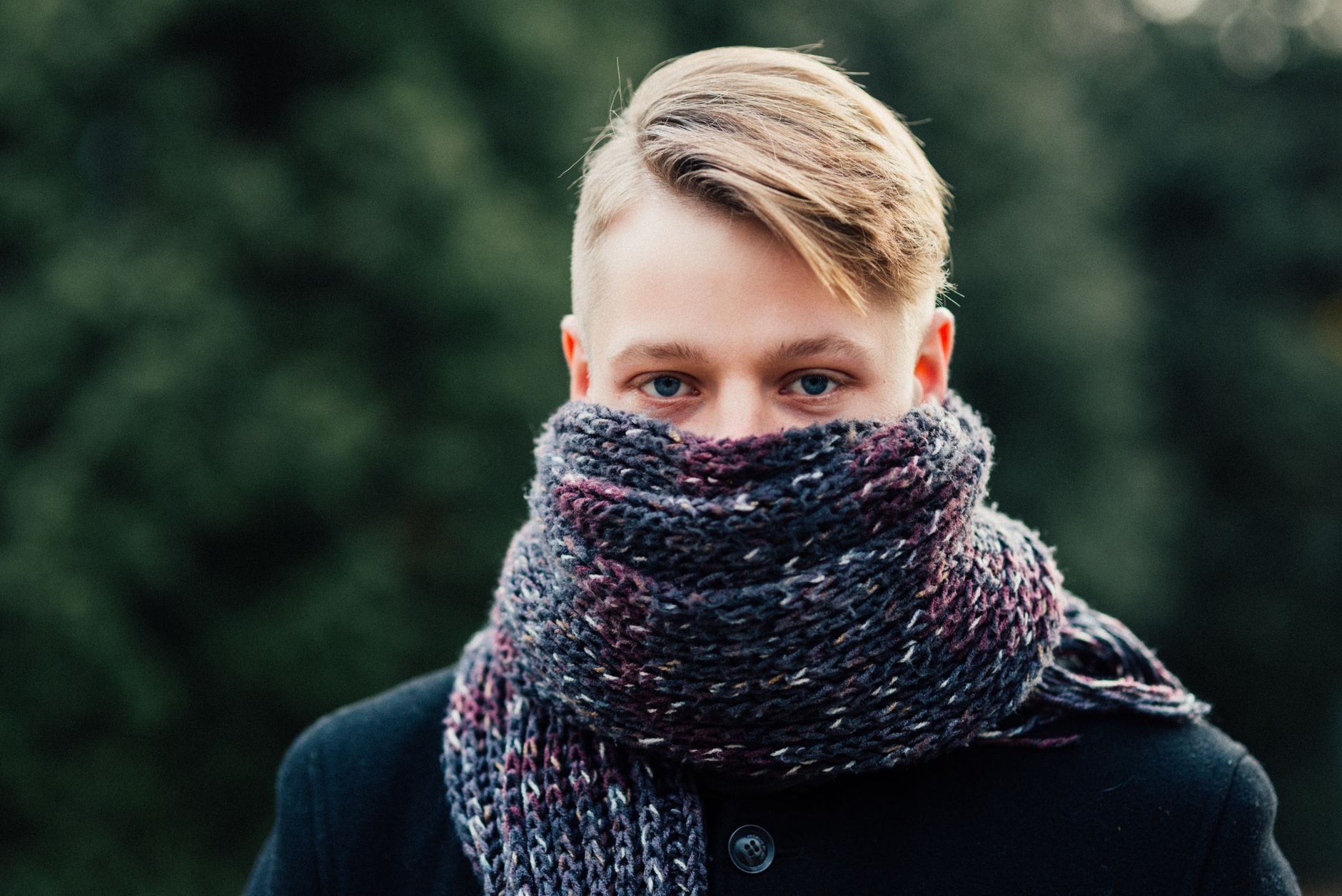 Portrait of a young man warmly dressed with a knitted scarf outdoors.