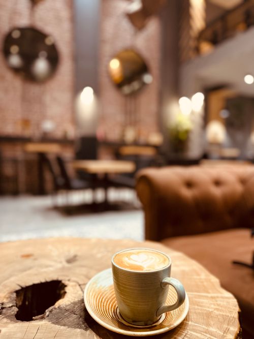 Free Aesthetic coffee cup with latte art on a rustic wooden table in a modern, stylish café. Stock Photo