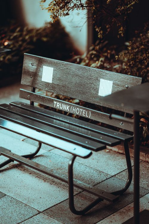 Free Wooden bench with 'Trunk Hotel' text on pavement in Tokyo, Japan, creating an urban vibe. Stock Photo