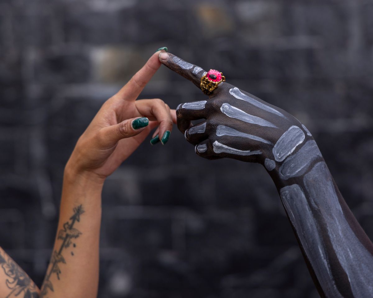 Close-up of painted hand with skeleton design and ornate ring, symbolizing Day of the Dead