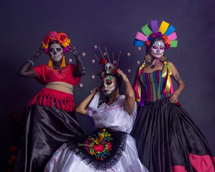 Colorful portrait featuring women in Dia de los Muertos costumes and makeup, embodying Mexican tradition.