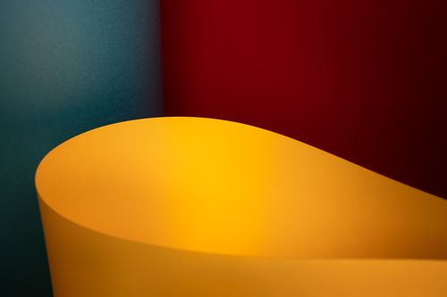 Free Artistic abstract composition of curved paper against a red and blue background. Stock Photo