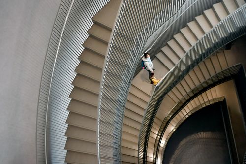 Free A woman walks down a spiral staircase in a modern building. Stock Photo
