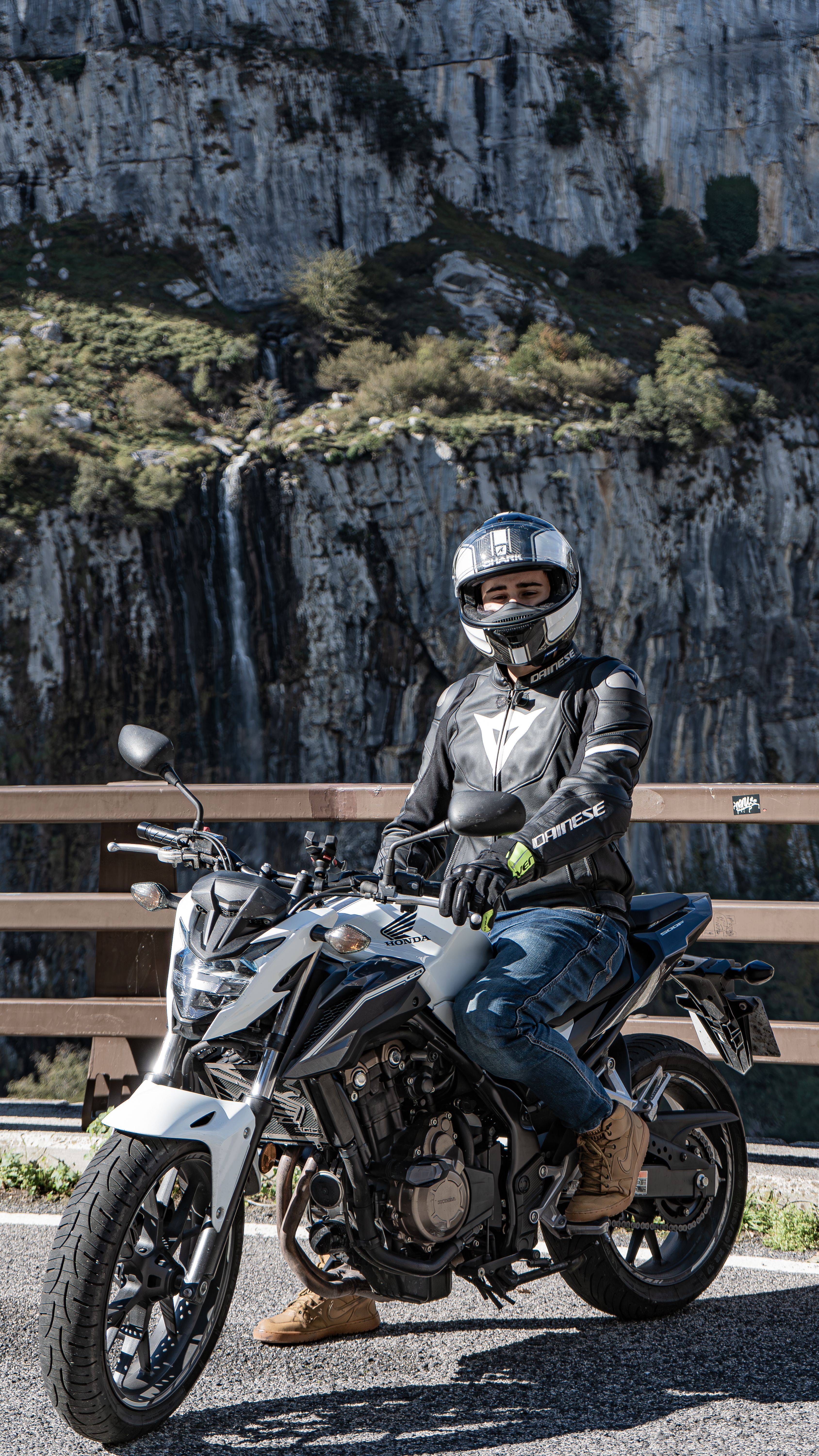 A motorcyclist in full gear poses with their bike against a stunning rocky landscape, ready for adventure.