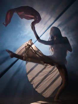 Artistic silhouette of a woman dancing gracefully with a flowing scarf.