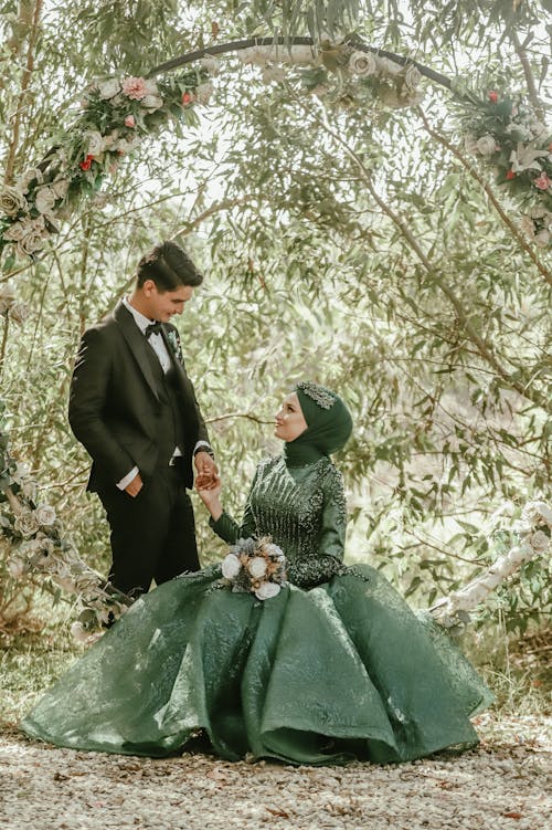 Bride in a Green Wedding Dress and Headscarf Holding Hands with a Groom in Tuxedo