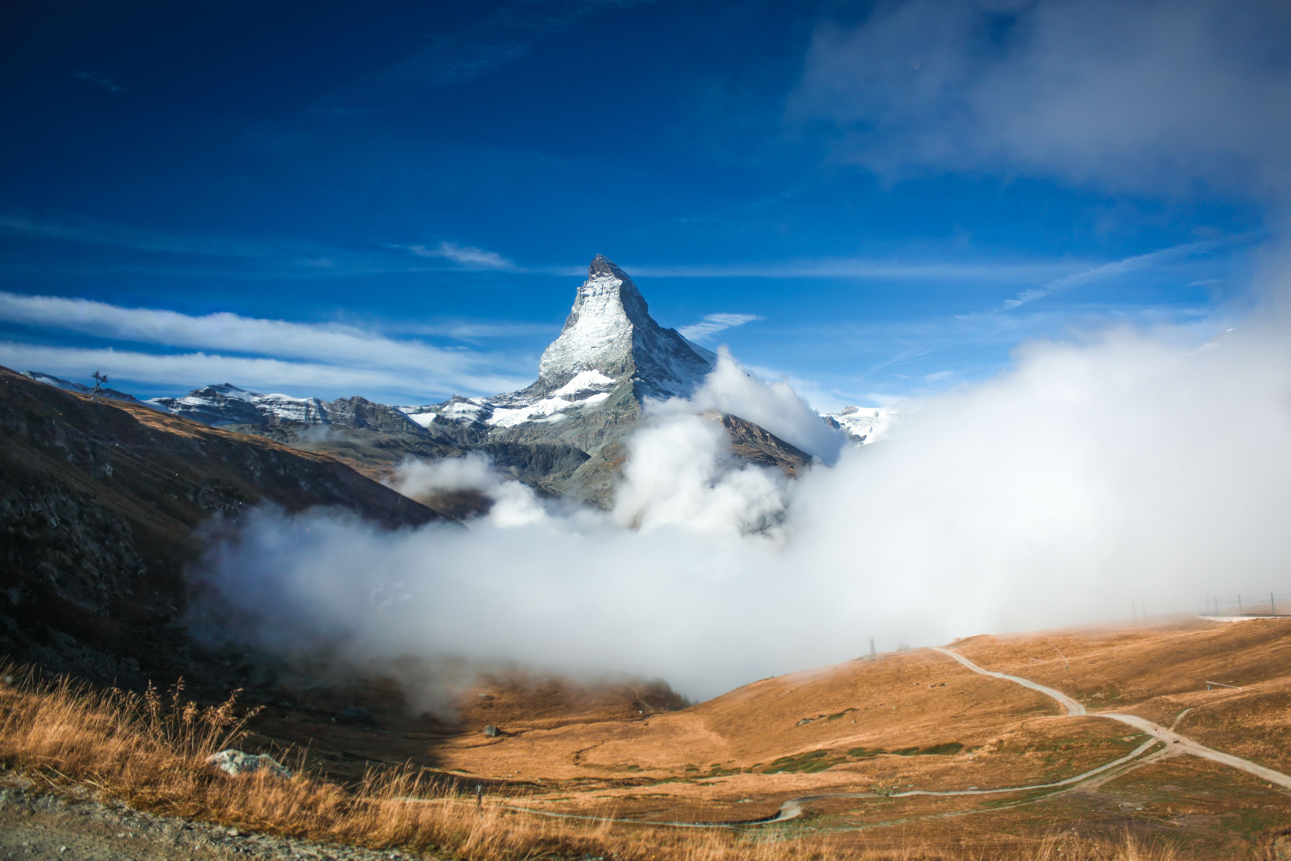 Scenic view of the Matterhorn surrounded by clouds and blue sky, captured in Zermatt, Switzerland.