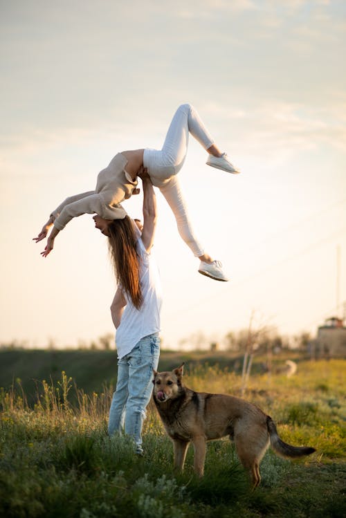 Man Lifting up Woman on Grassland at Sunset