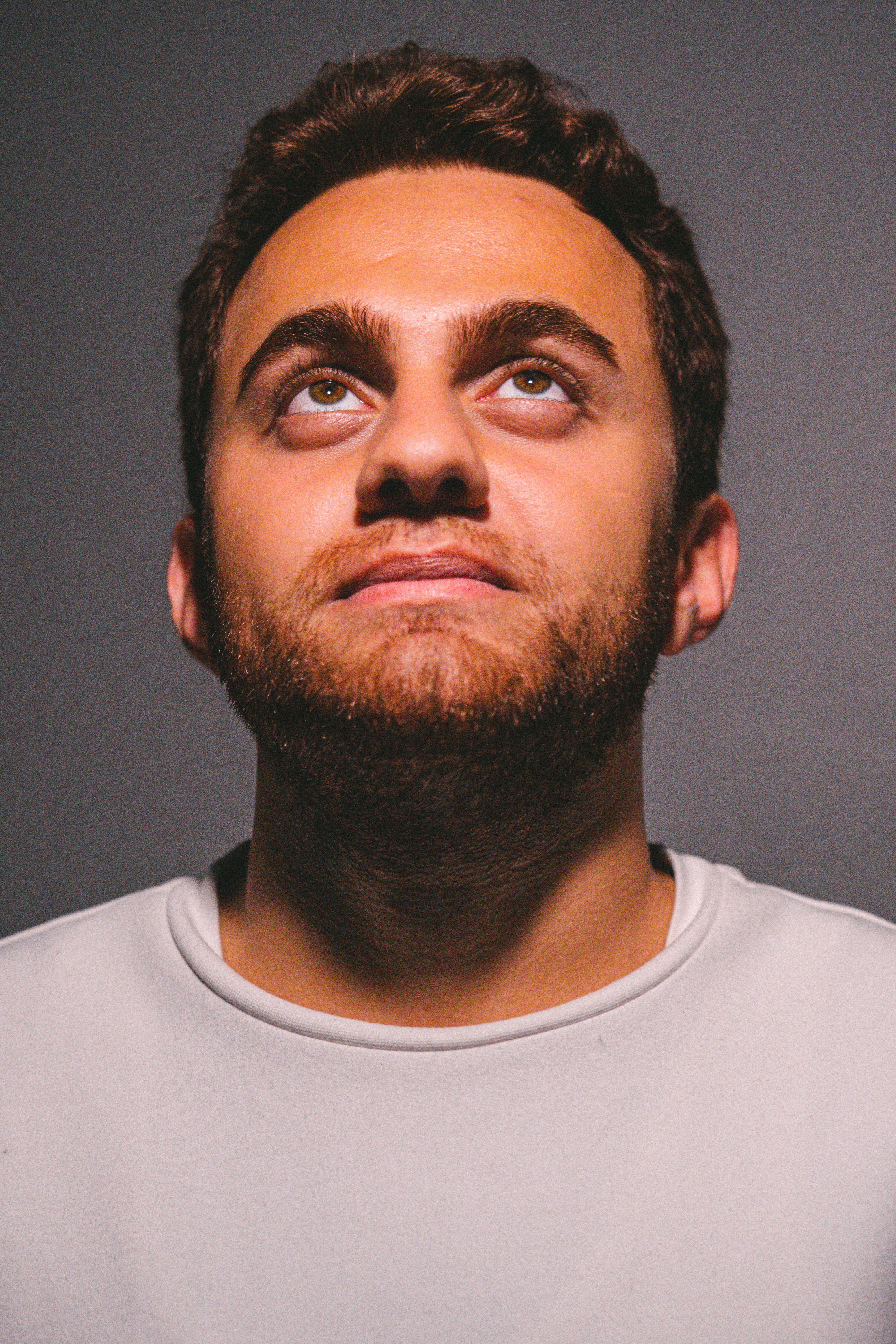 Portrait of a confident young man gazing upward against a gray background. Ideal for conceptual themes.