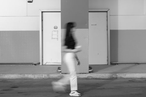 Free Artistic black and white photo capturing urban street life with motion blur effect of a walking woman. Stock Photo