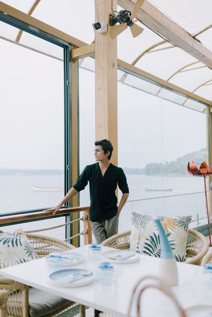 Elegant man enjoying a peaceful view at a seaside restaurant with stylish decor.