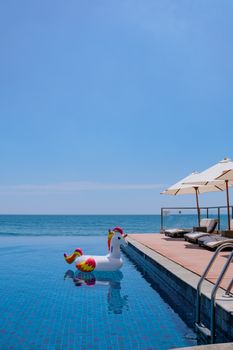 Relaxing poolside scene with unicorn float near the ocean in summer.