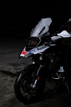 A close-up view of an adventure motorcycle with raindrops in a dark setting, emphasizing sleek design.