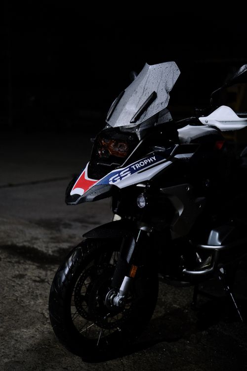 Free A close-up view of an adventure motorcycle with raindrops in a dark setting, emphasizing sleek design. Stock Photo