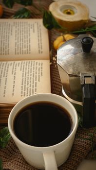 Warm setting with a coffee cup, book, and stovetop espresso maker. Perfect for relaxation themes.