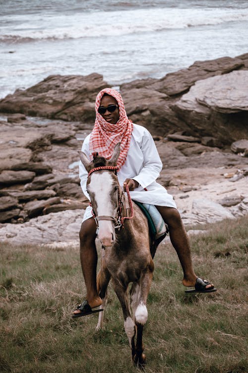 Man Wearing a Beduin Scarf Riding a Horse on a Shore