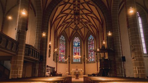 A beautiful Gothic church interior showcasing stained glass windows and vaulted ceiling.