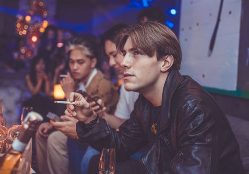 Free Group of young adults enjoying nightlife in a dimly lit lounge with drinks and social atmosphere. Stock Photo