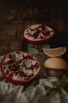 Moody still life of cut pomegranate and citrus fruits, earthy tones.