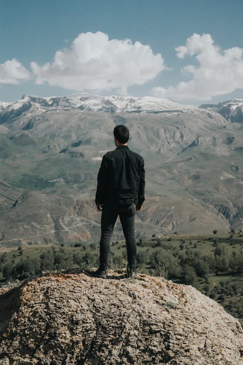 Man Standing on a Rock and Looking at the Mountains 