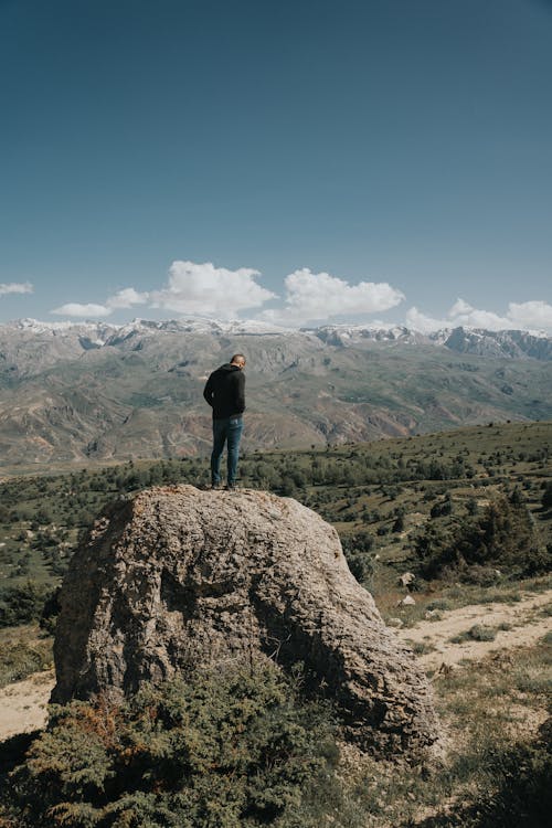 Man Standing on a Rock and Looking at the Mountains 