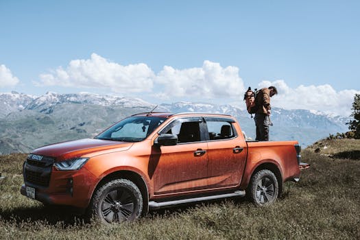 Orange pickup truck with traveler in scenic mountain location, perfect for adventure themes.