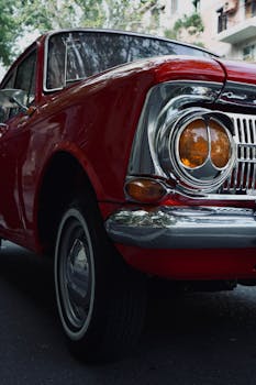 Close-up of a classic red vintage car with chrome details, capturing its retro essence.