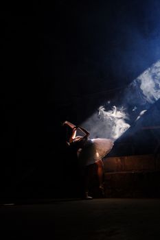 A ballerina gracefully dances in a spotlight with dramatic lighting effects.