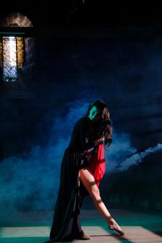 A woman in a dramatic dance pose with smoky effects and low light creating a mysterious atmosphere.