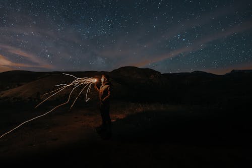 Man Light Painting under a Starry Sky at Night
