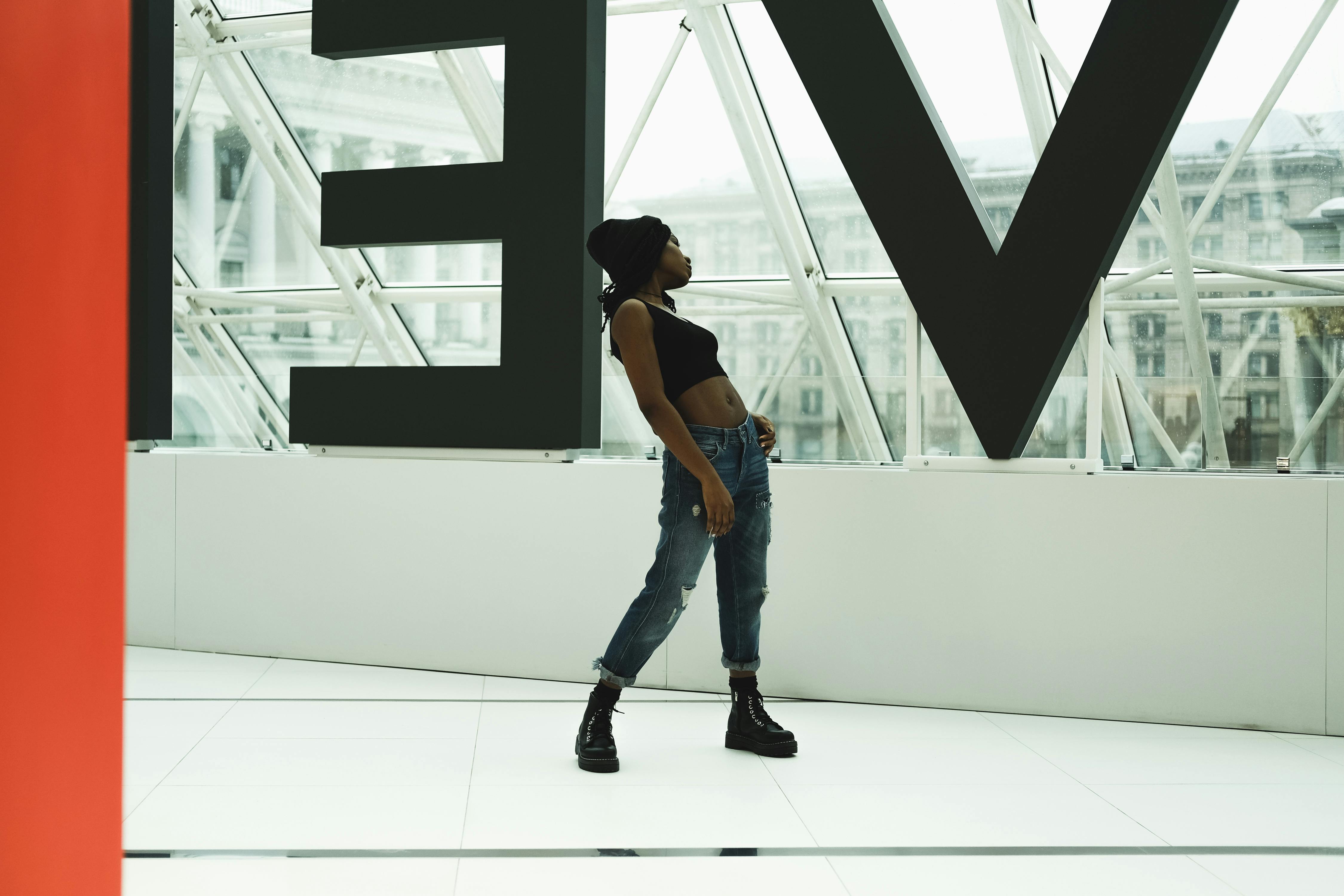 一位穿着露脐上衣和牛仔裤的时尚女性在室内与几何建筑合影