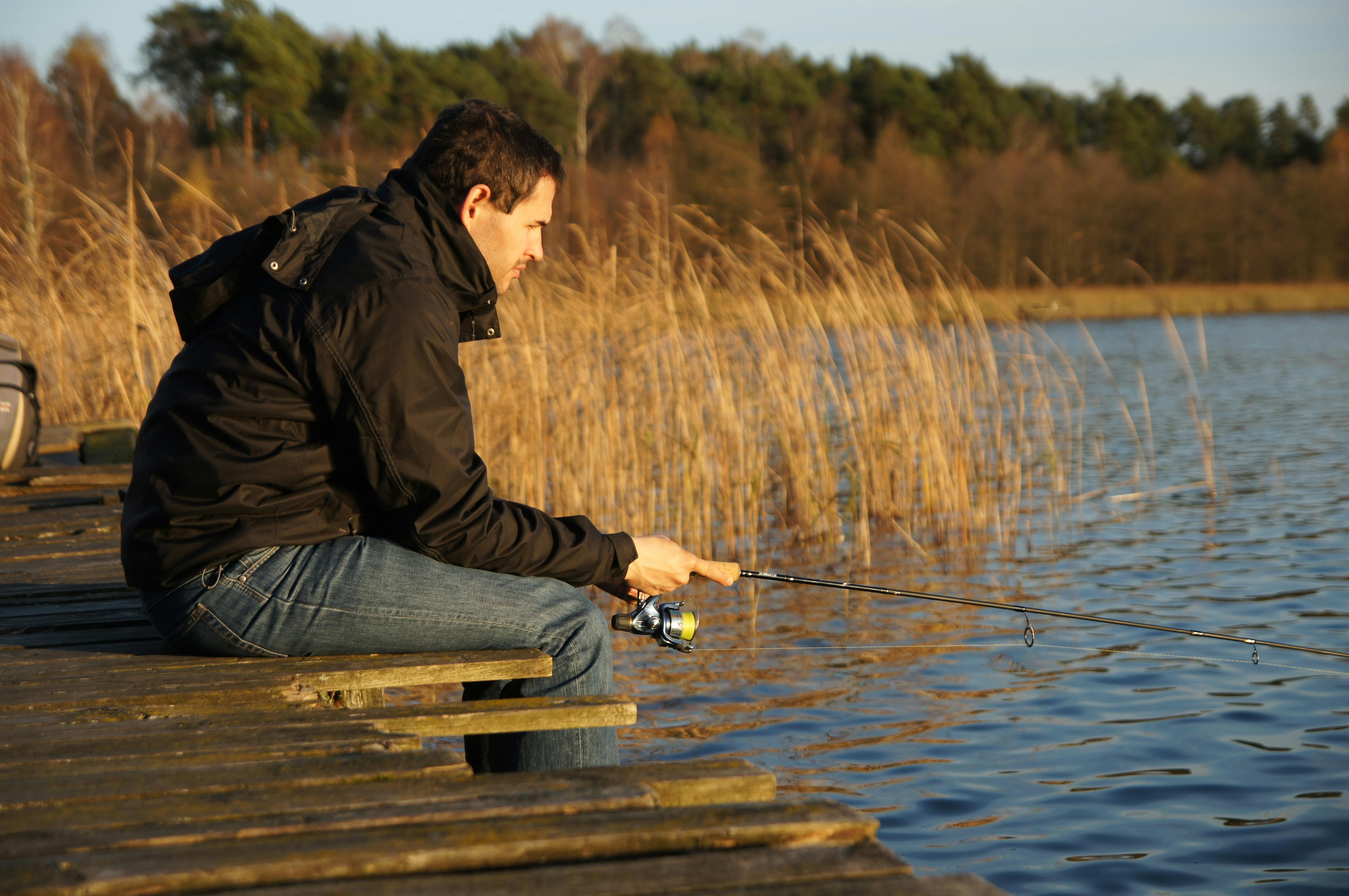 A man sitting on a dock fishing · Free Stock Photo