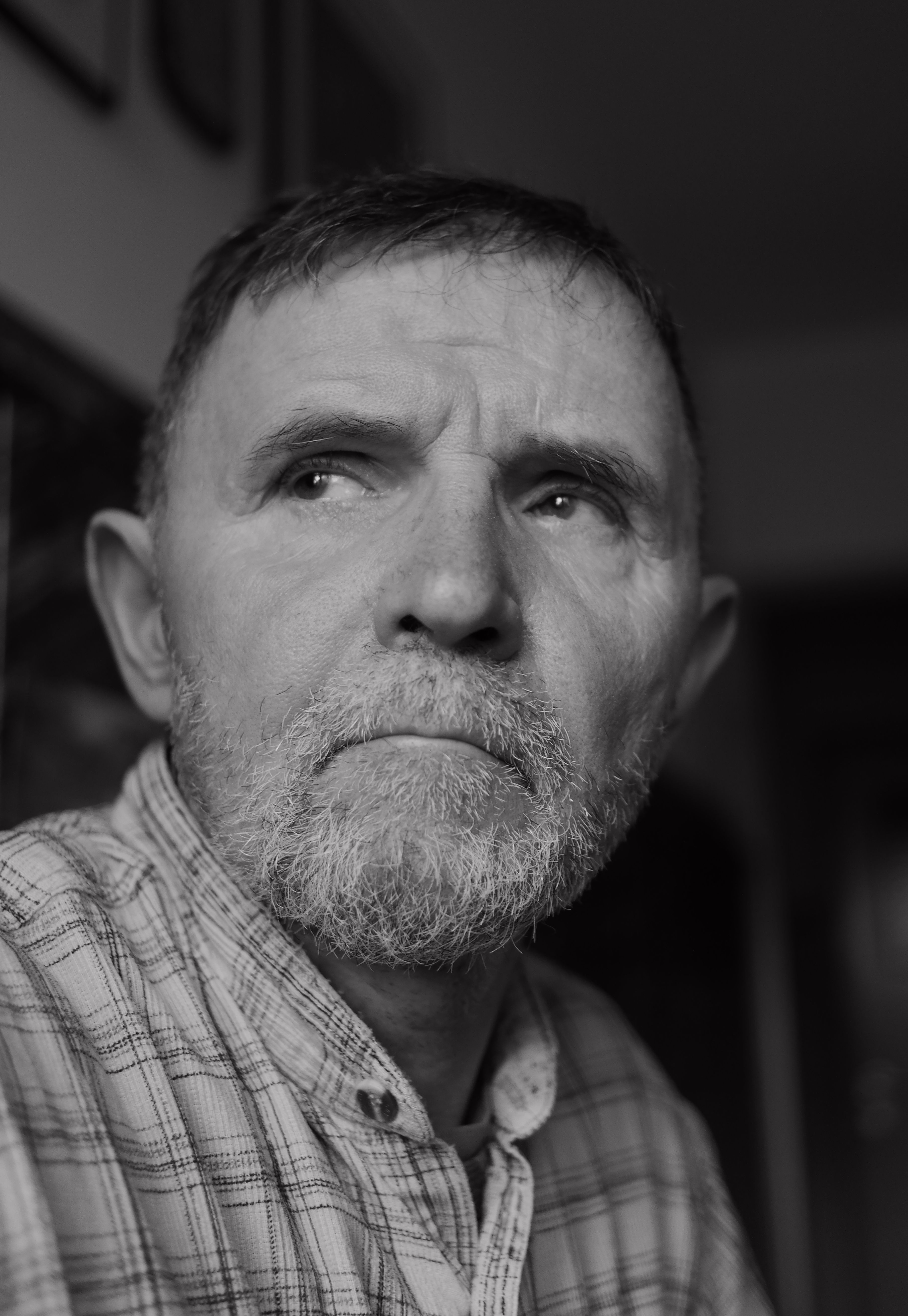A thoughtful black and white portrait of an elderly man with facial hair, expressing introspection.