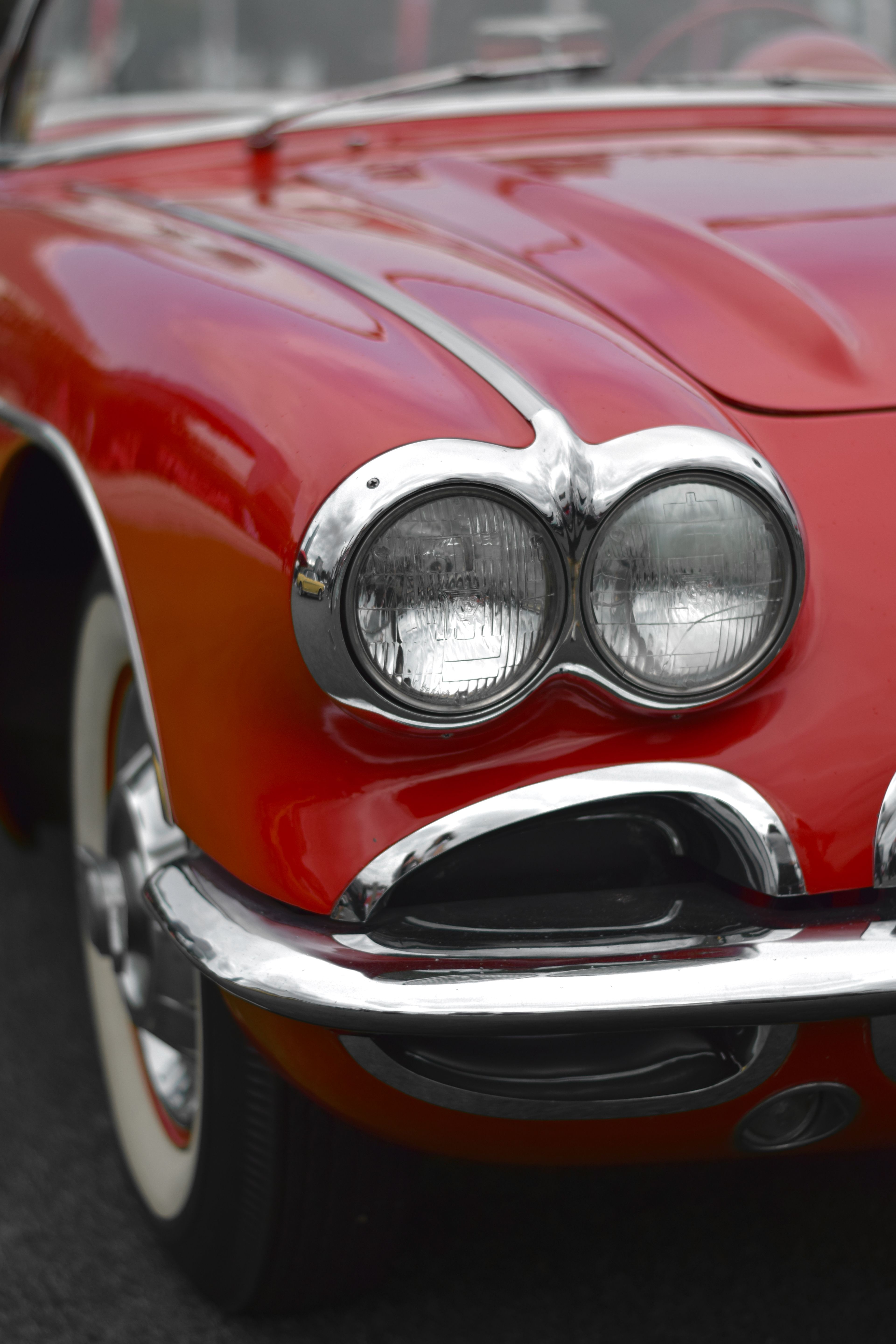 Close-up shot of a classic red vintage car with prominent headlights and chrome detailing.