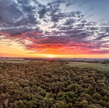 A stunning aerial view of a lush forest at sunset in Pepin, WI, showcasing vibrant skies and serene nature.