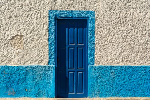 Free Close-up of a vibrant blue door on a rustic white wall in El Cotillo, Spain. Stock Photo