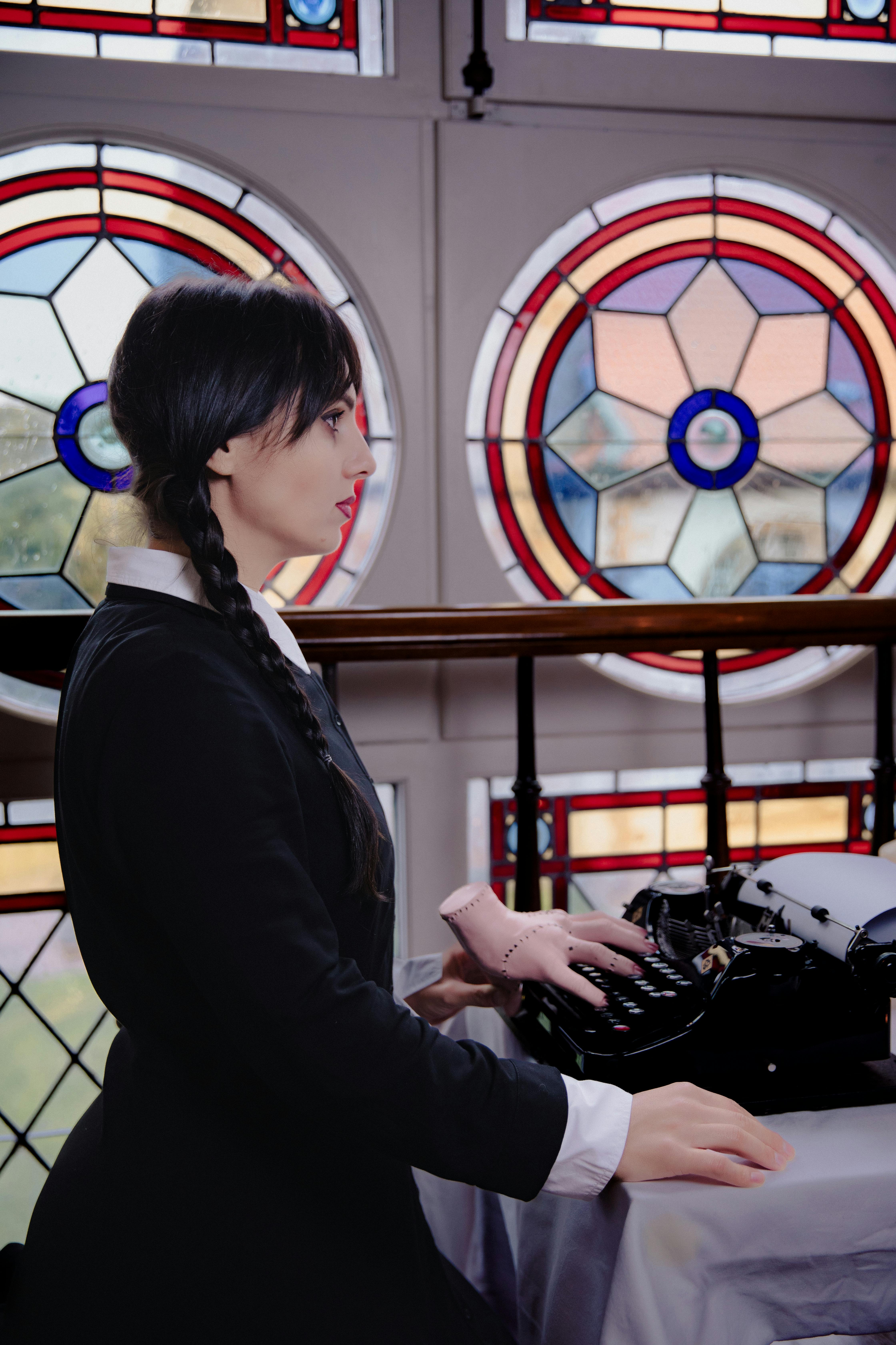 girl in the wednesday addams costume writing on a typewriter