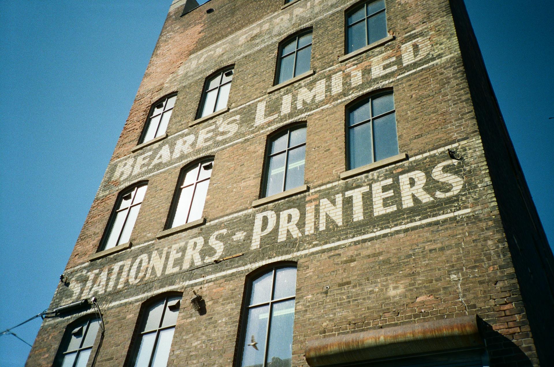 Low-angle shot of an old brick building featuring vintage painted advertisements.