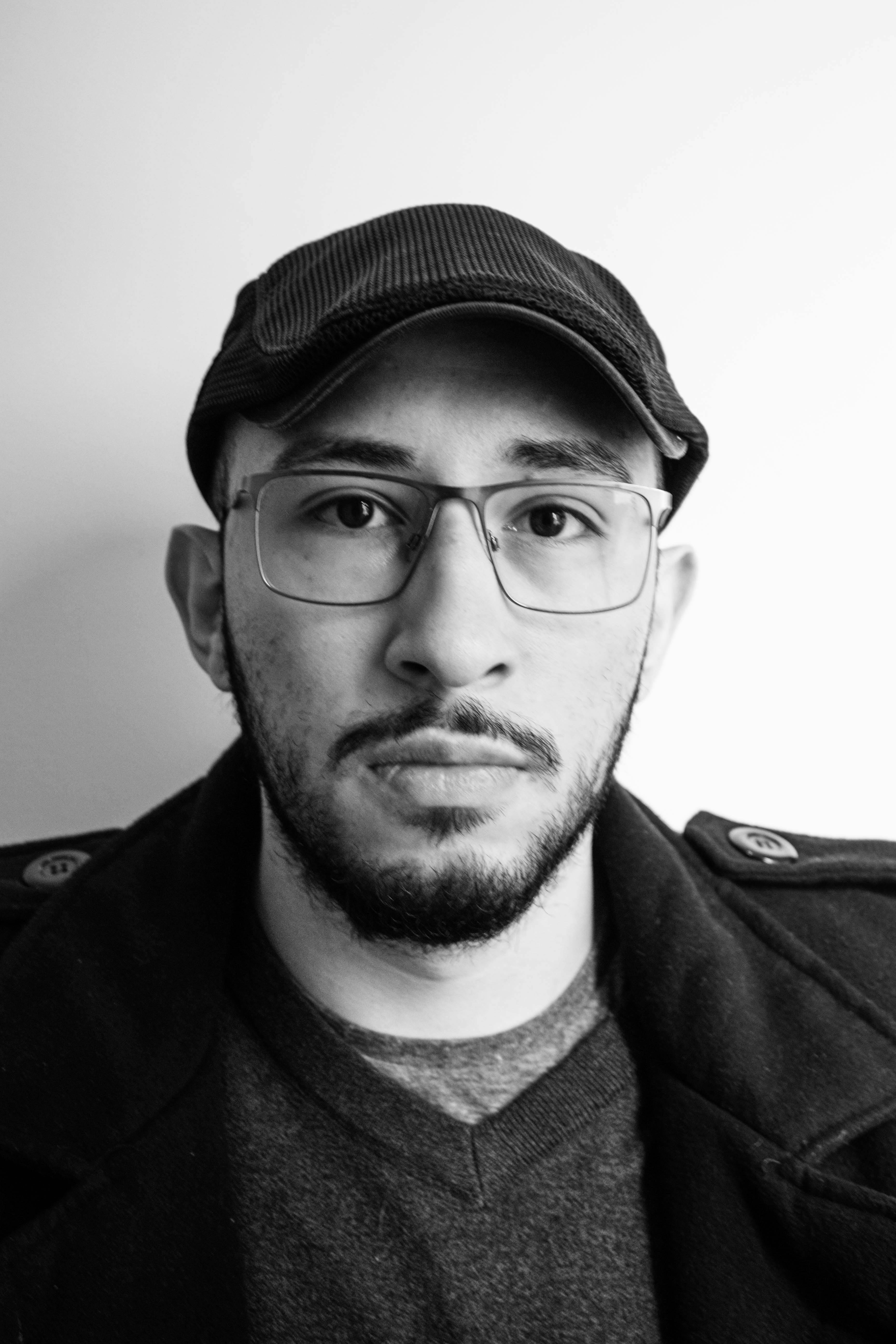 Free Striking black and white portrait of a man wearing glasses and a cap, captured in a studio setting. Stock Photo