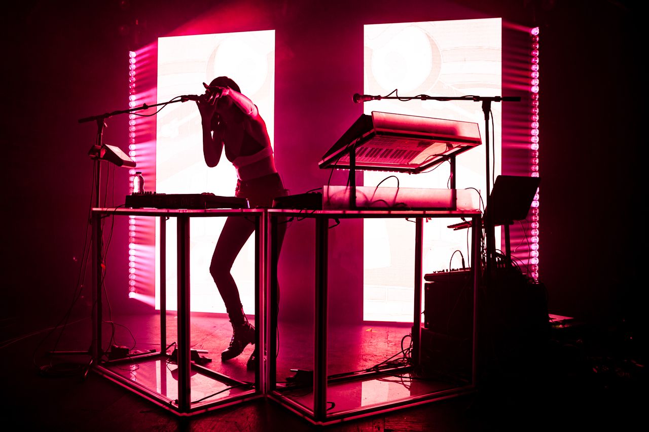 Silhouette of a DJ performing live electronic music with vibrant lighting