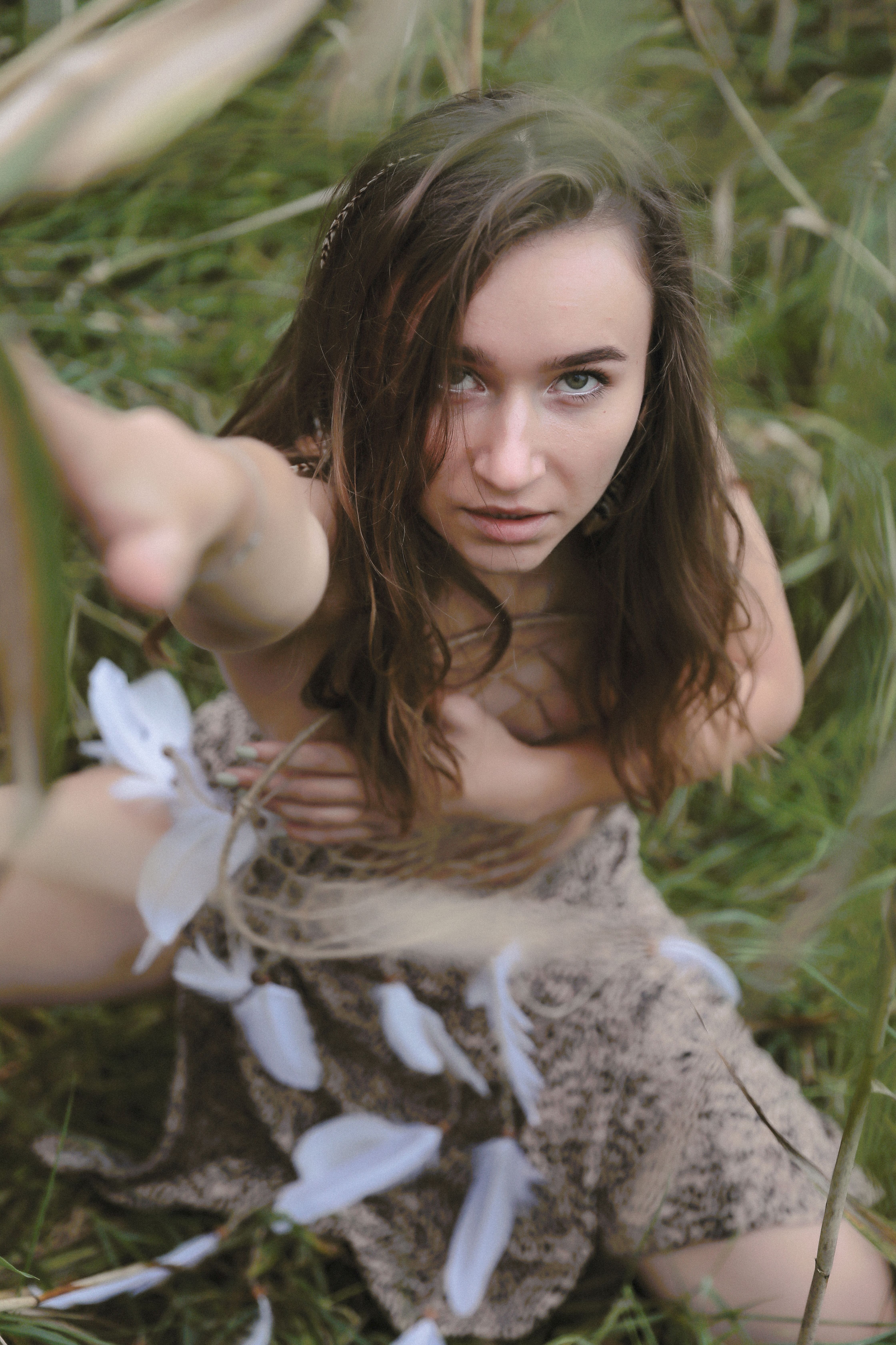 Portrait of a young woman reaching out among green foliage.