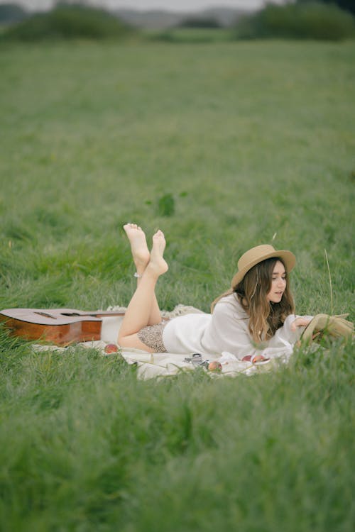 Woman Lying on a Field with a Guitar