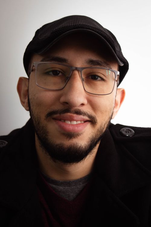 Free Casual portrait of a smiling man in glasses and a hat, showcasing a friendly expression. Stock Photo