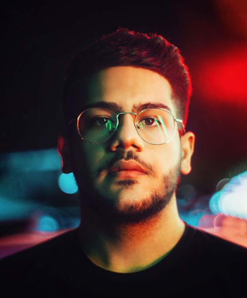 Free Vibrant night portrait of a young man with glasses and beard under colored lights. Stock Photo