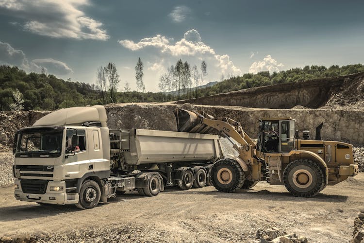 Front Load Loader Beside White Dump Truck